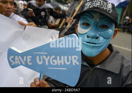 Un activiste du Forum de la communauté islamique centrale de Sulawesi (FUI) a porté une brochure qui a lu « Save Uyghur » lors d'un rassemblement devant le Bureau du Conseil du représentant régional du peuple central de Sulawesi à Palu, dans le centre de Sulawesi, en Indonésie, sur 20 décembre 2019. Ils ont demandé au gouvernement indonésien, par le biais d'une politique étrangère libre et active, de prendre le rôle d'exhorter le gouvernement chinois à donner la liberté et non pas à limiter les musulmans ouïghours dans la pratique du culte. (Photo de Basri Marzuki/NurPhoto) Banque D'Images