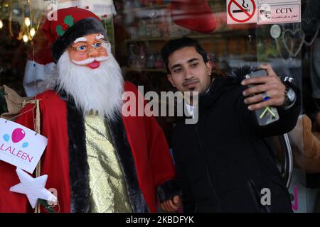 Un jeune palestinien prend un selfie devant un personnage du Père Noël exposé devant un magasin de la ville de Gaza sur 26 décembre 2019. (Photo de Majdi Fathi/NurPhoto) Banque D'Images