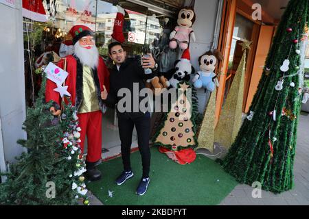 Un jeune palestinien prend un selfie devant un personnage du Père Noël exposé devant un magasin de la ville de Gaza sur 26 décembre 2019. (Photo de Majdi Fathi/NurPhoto) Banque D'Images