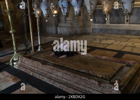 Un pèlerin touche la Pierre de l'onction à Jérusalem, Israël, le 10 décembre 2019. Situé en face de l'entrée de l'église, ce coin du Saint-Sépulcre est considéré comme l'endroit où le corps de Jésus a été oint après avoir été abaissé de la croix. (Photo de Joaquin Gomez Sastre/NurPhoto) Banque D'Images