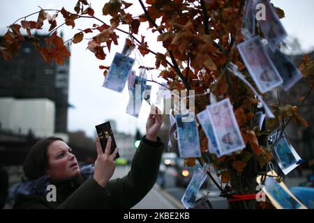 Une femme prend une photo de la spoof 'Bank of Brexitlies' 350m notes portant la face du Premier ministre Boris Johnson et du principal député Brexiteer Jacob Rees-Mogg attaché à un 'arbre de la Banque des Brexitlies' établi par des militants anti-Brexit devant le Parlement à Londres, en Angleterre, sur 7 janvier 2020. Lors de la campagne du référendum de 2016, les sortants ont faussement affirmé que 350m étaient envoyés chaque semaine dans l'UE, ce qui pourrait être dépensé au service national de santé. Le Royaume-Uni est sur le point de quitter l'UE à 11pm ans sur 31 janvier, en commençant une période de transition qui va jusqu'à la fin de l'année, à l'époque de Premier Ministre Banque D'Images