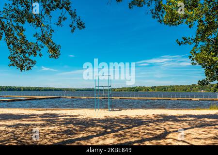 Vue sur le lac de Paprocańskie à Tychy. Plates-formes en bois au premier plan. Plantes aquatiques et voiliers. Une belle journée ensoleillée. Plage de sable dans lumière a Banque D'Images