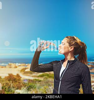 Rafraîchi et prêt à fléchir. Une jeune femme sportive qui boit de l'eau à l'extérieur. Banque D'Images