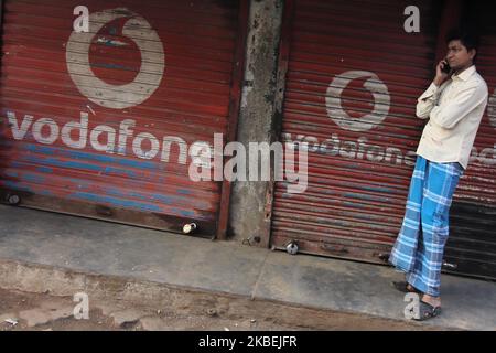 Le 15 janvier 2020, un homme parle sur un téléphone portable à l'extérieur des volets d'un magasin peint avec le logo de Vodafone à Mumbai, Inde. (Photo par Himanshu Bhatt/NurPhoto) Banque D'Images