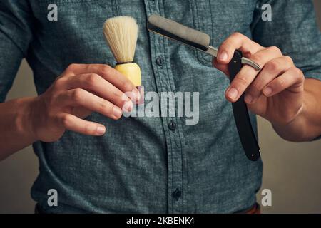 Prenez le temps de vous raser, un jeune homme charmant tenant un rasoir droit et une brosse à rasoir dans les mains. Banque D'Images