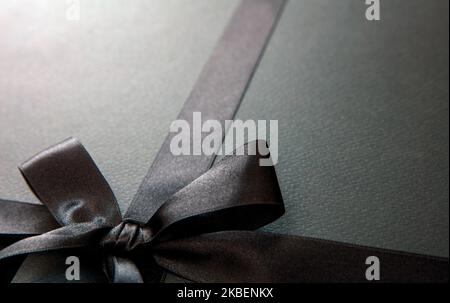 Vente du Vendredi fou et cadeaux de Noël. Ruban en satin noir et noeud, vue rapprochée. Banque D'Images