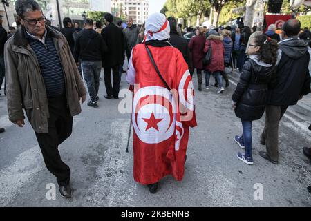 Une personne âgée vêtue du drapeau tunisien, se promène avec une béquille lors des célébrations du 9th anniversaire de la révolution qui s'est tenue sur l'avenue Habib Bouguiba, dans la capitale Tunis, en Tunisie, sur 14 janvier 2020. (Photo de Chedly Ben Ibrahim/NurPhoto) Banque D'Images