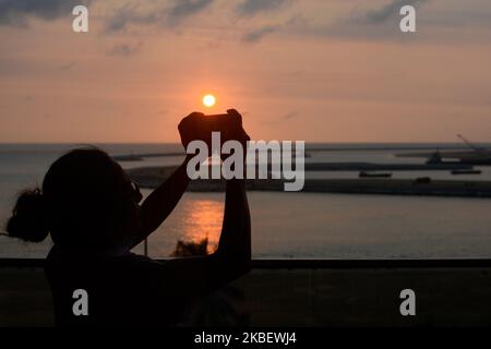 Une femme prend une photo coucher de soleil soir, arrière-plan vu sous construction Colombo International Financial City (Port City) à Colombo, Sri Lanka le 17 janvier 2020. La ville de Finance doit être construite entre le bord sud du nouveau port sud de Colombo et le phare de fort. La superficie totale de la mer à reprendre est de 269 ha (660 acres). Colombo, Sri Lanka. (Photo d'Akila Jayawardana/NurPhoto) Banque D'Images