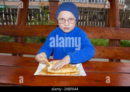 garçon assis dans des verres et mange des chebureks avec de la viande Banque D'Images