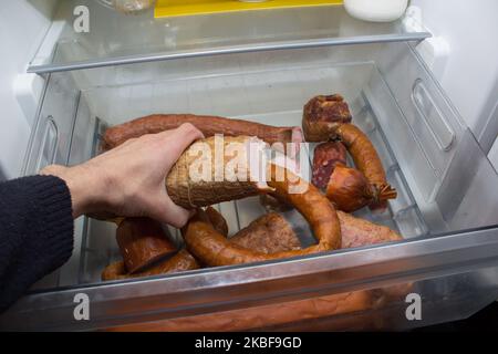 main d'homme tient les saucisses du réfrigérateur Banque D'Images