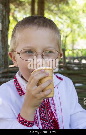 Un garçon ukrainien dans une chemise brodée mange de la glace Banque D'Images