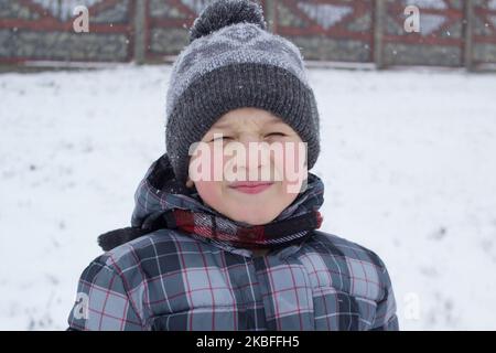 En hiver, le garçon vêtu d'un capuchon fermait les yeux Banque D'Images