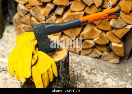 ax coincé dans une terrasse en bois et gants de protection en cuir jaune Banque D'Images