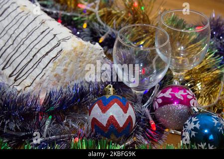 Noël ou nouvel an. Champagne dans des verres avec bougies, panettone et cadeau avec noeud en satin rouge. Espace-copie. Concept festif Banque D'Images