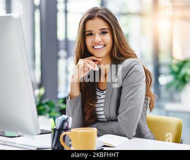 Je me sens positif au sujet de mon travail. Portrait court d'une jeune femme d'affaires attirante assise à son bureau. Banque D'Images