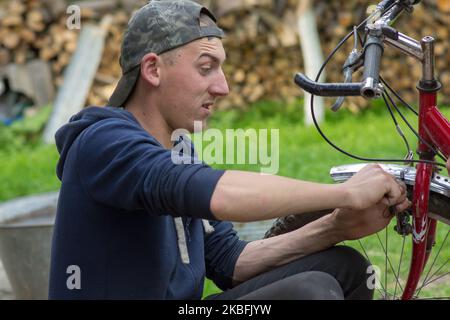 Homme avec des émotions frein de vélo réparé dans la cour Banque D'Images