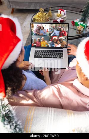 Couple biracial avec décorations de noël ayant appel vidéo avec des amis heureux divers Banque D'Images