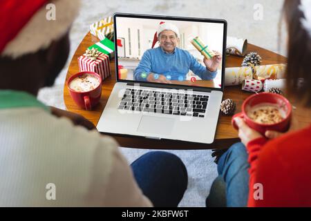 Divers couple avec décorations de noël ayant appel vidéo avec heureux homme biracial Banque D'Images