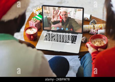 Divers couple avec des décorations de noël ayant appel vidéo avec l'homme caucasien heureux Banque D'Images