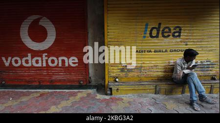 Un homme utilise un téléphone portable à l'extérieur des volets d'un magasin peint avec un logo de Vodafone à Mumbai, Inde, le 02 février 2020. (Photo par Himanshu Bhatt/NurPhoto) Banque D'Images