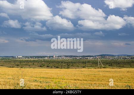 Un beau paysage de chaume de blé avec des nuages noirs sur le fond de la ville Banque D'Images