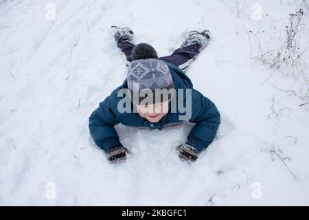 le garçon est tombé à la neige vers l'avant sur le ventre Banque D'Images