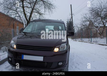 le conducteur s'assoit dans la voiture en hiver dans la rue des maisons privées Banque D'Images