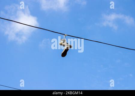 Baskets attrapés sur un fil téléphonique contre le ciel Banque D'Images