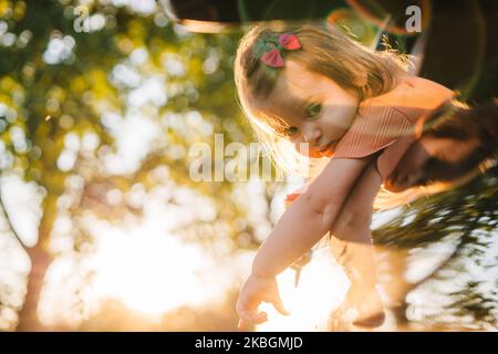 La petite fille qui colle la tête hors de la fenêtre de la voiture et regarde les reflets des rayons du soleil sur la voiture. Bonne famille, enfance. Heureux Banque D'Images