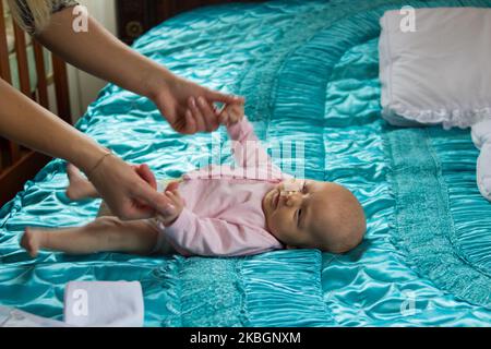 une mère heureuse tient un bébé sur les mains dans le lit Banque D'Images