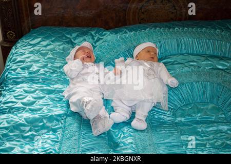 bébé fille et garçon jumeaux sont habillés en blanc sur le grand lit Banque D'Images