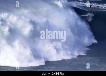 Les surfeurs de grandes vagues Andrew Cotton de Grande-Bretagne (en bas) et Hugo Vau du Portugal (en haut) lâcher une vague pendant le défi de surf de remorquage de Nazare WSL à Praia do Norte à Nazare, Portugal sur 11 février 2020. (Photo par Pedro Fiúza/NurPhoto) Banque D'Images