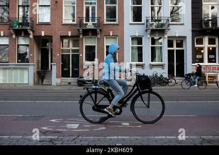 Les personnes utilisant des vélos dans la ville et/ou des stations de recharge de voiture électrique à Amsterdam vu sur 17 février 2019. Amsterdam est équipé d'un large réseau de pistes cyclables, si sûr et confortable que même les tout-petits et les personnes âgées utilisent les vélos comme mode de transport le plus facile. Les vélos sont couramment utilisés dans d'autres villes comme la Haye et Rotterdam. Les voitures et motos fonctionnant à l'essence et au diesel seront interdites d'Amsterdam à partir de 2030 dans le but de nettoyer l'air de la ville, a déclaré le conseil de la capitale néerlandaise en 2019. L'utilisation de véhicules électriques est en augmentation dans la ville. Une passe est nécessaire pour charger Banque D'Images