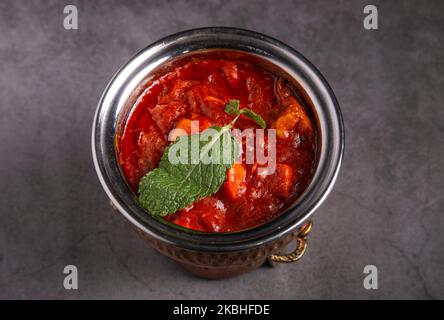Poulet épicé rougeâtre / curry de Masala, servi dans un bol ou Kadhai sur fond rustique Banque D'Images