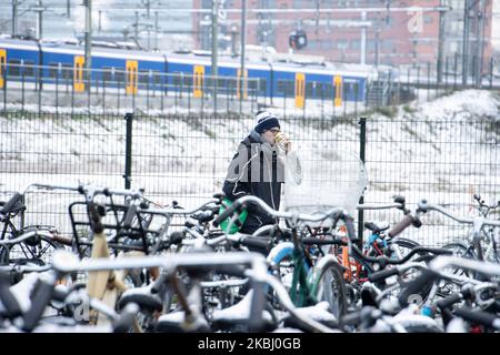 Un jeune homme boit une boisson chaude sur les vélos. Les Hollandais à vélo, à vélo après la chute de neige dans le froid. Piles de milliers de bicyclettes garées à l'extérieur de la gare centrale d'Eindhoven Centraal. Images de la vie quotidienne du centre-ville après la chute de neige dans la ville d'Eindhoven sur 26 février 2020. La première neige pour l'hiver 2019-2020 avec de basses températures pour la région suivie d'une légère pluie. (Photo de Nicolas Economou/NurPhoto) Banque D'Images