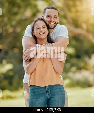 Un jeune couple qui s'enserre dans un parc, un jardin et la nature pour l'amour, le soin et le romantisme, s'encadre en plein air en Colombie. Portrait de sourire, rire et se détendre Banque D'Images