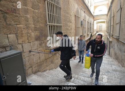 Deux hommes pulvérisent une main courante sur une rue concourant à la rue via Dolorosa, une route processionnelle dans la vieille ville de Jérusalem, considérée comme le chemin que Jésus a marché sur le chemin de sa crucifixion. Le ministère de la Santé d'Israël vient d'annoncer que trois autres personnes ont reçu un diagnostic de coronavirus, ce qui porte le nombre total à 42 Israéliens et 25 Palestiniens testés positifs pour le coronavirus. Des milliers de personnes sont encore isolées et Israël pourrait étendre la quarantaine du coronavirus aux visiteurs de tous les pays. Lundi, 9 mars 2020, à Jérusalem, Israël. (Photo par Artur Widak/NurPhoto) Banque D'Images