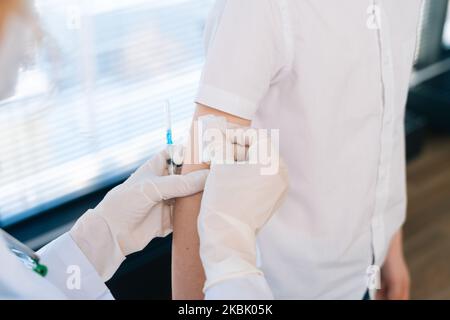 Gros plan de prise de vue d'une femme médecin méconnue appliquant du plâtre sur l'épaule de l'enfant garçon après l'injection de la vaccination. Banque D'Images