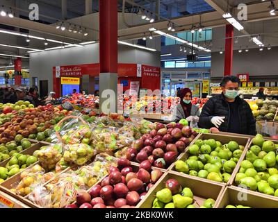 Homme portant des gants chirurgicaux et un masque facial pour se protéger lorsqu'il fait ses courses dans une épicerie de 13 mars 2020, à Toronto, en Ontario, au Canada. Les épiceries ont été remplies de grandes foules et de longues files d'attente, car la dernière pointe de nouveaux cas de coronavirus (COVID-19) a provoqué des achats de panique dans tout le pays. Les Canadiens se sont précipités dans les épiceries et les marchés pour stocker des fournitures comme du papier hygiénique et des conserves. Dans de nombreux magasins tout au long de la soirée, les files d'attente ont non seulement empêché les gens de naviguer dans le magasin, mais elles se sont également enroulées autour des allées car des chariots à provisions surchargés ont étouffé chaque centimètre de spa Banque D'Images