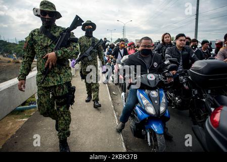 Les automobilistes qui tentent de traverser une frontière à Quezon City, aux Philippines, s'accumulent dans un point de contrôle sur 16 mars 2020. La région métropolitaine de Manille est mise en quarantaine depuis dimanche, à 16 mars, afin de freiner la propagation de la COVID-19. Des policiers et des soldats de l'armée surveillent l'entrée et la sortie de la région de la capitale.(photo de Lisa Marie David/NurPhoto) Banque D'Images