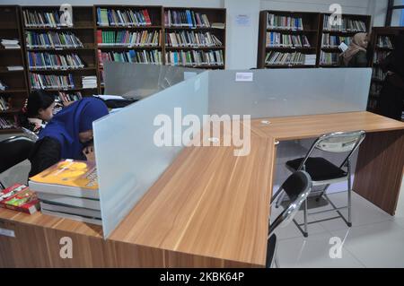 Deux bancs vides se trouvent juste devant les étudiantes qui terminent leurs devoirs de campus à la table de lecture de la Bibliothèque régionale centrale de Sulawesi, sur 18 mars 2020. L'autorité centrale du gouvernement de la santé de Sulawesi a imposé des restrictions à ses citoyens pour des activités à l'extérieur du foyer, après que quatre personnes aient été traitées pour des personnes soupçonnées d'être infectées par Covid-19. (Photo de Faldi Muhammad/NurPhoto) Banque D'Images