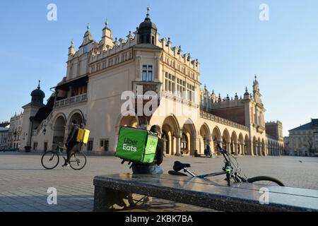 Un Uber mange et des conservateurs de Glovo vus sur une place du marché vide de Cracovie. Les entreprises alimentaires locales s'adaptent à une nouvelle réalité du coronavirus en fournissant des services de livraison incresed à leurs clients. Le ministère de la Santé a annoncé 13 nouveaux cas de coronavirus en Pologne, portant le nombre total à 251. Mercredi, 18 mars 2020, à Cracovie, en Pologne. (Photo par Artur Widak/NurPhoto) Banque D'Images