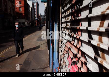 Un homme portant un masque passe devant un magasin d'accessoires à volets sur la rue Berwick à Soho, à Londres, en Angleterre, sur 21 mars 2020. Une grande partie du centre de Londres était pratiquement vide aujourd’hui, un jour après que le Premier ministre britannique Boris Johnson ait ordonné la fermeture de tous les pubs, bars, cafés et restaurants du pays. Cette décision constitue un renforcement des mesures visant à faire respecter la « distanciation sociale » qui est pressée pour les citoyens de réduire la croissance des infections au coronavirus covid-19. Des boîtes de nuit, des théâtres, des cinémas, des salles de sport et des centres de loisirs ont également été commandés fermés. Il restait des boutiques dans le centre de la capitale Banque D'Images