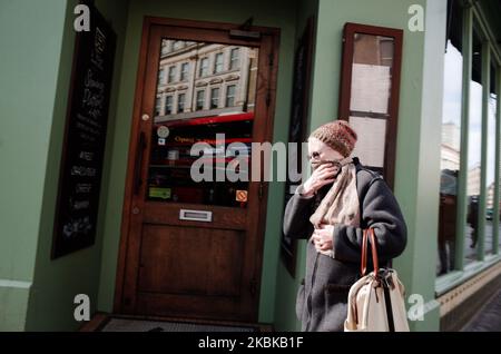 Une femme âgée couvre son visage avec un foulard sur une route de Tottenham court presque déserte à Londres, en Angleterre, sur 21 mars 2020. Une grande partie du centre de Londres était pratiquement vide aujourd’hui, un jour après que le Premier ministre britannique Boris Johnson ait ordonné la fermeture de tous les pubs, bars, cafés et restaurants du pays. Cette décision constitue un renforcement des mesures visant à faire respecter la « distanciation sociale » qui est pressée pour les citoyens de réduire la croissance des infections au coronavirus covid-19. Des boîtes de nuit, des théâtres, des cinémas, des salles de sport et des centres de loisirs ont également été commandés fermés. Il restait des boutiques dans le centre de la capitale Banque D'Images