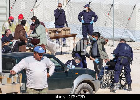 Un homme adulte et un handicapé sont contrôlés par la police avant d'entrer dans le camp, tandis que d'autres collectent des lits et des oreillers pour leur séjour dans les tentes. Un nouveau camp de réfugiés et de migrants en Grèce, dans la région de Kleidi près du village de Promakhonias dans la région de Serres, aux frontières grec - bulgare, reçoit la première vague de personnes, demandeurs d'asile qui sont entrés en Grèce après le 1st mars 2020, où le pays a cessé d'accepter des demandes d'asile. Les nouveaux arrivants sont des îles Lesvos, Samos et Chios et ont été transférés par ferry à Kavala puis à Kleidi en bus afin des enregistrer, phot Banque D'Images