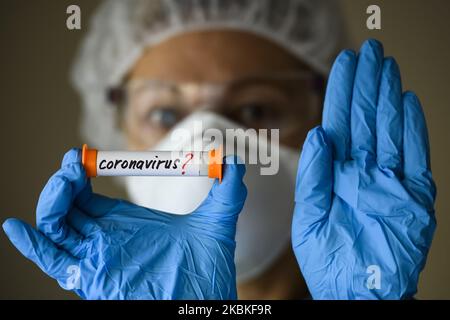 Femme en costume de protection, respirateur et lunettes tenant un tube à essai avec un échantillon d'analyse suspecté d'être infecté par le coronavirus COVID-19 à Kiev, Ukraine, on 23 mars 2020. (Photo Illustration par Maxym Marusenko/NurPhoto) Banque D'Images