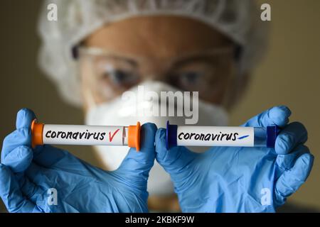 Femme en costume de protection, respirateur et lunettes tenant des tubes à essai avec échantillon d'analyse infectés et non infectés par le coronavirus COVID-19 à Kiev, Ukraine, on 23 mars 2020. (Photo Illustration par Maxym Marusenko/NurPhoto) Banque D'Images