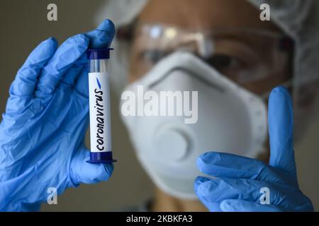 Femme en costume de protection, respirateur et lunettes tenant un tube à essai avec un échantillon d'analyse non infecté par le coronavirus COVID-19 à Kiev, Ukraine, on 23 mars 2020. (Photo Illustration par Maxym Marusenko/NurPhoto) Banque D'Images