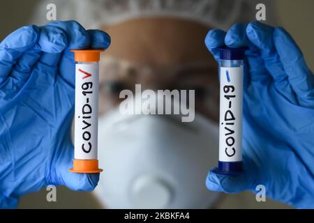 Femme en costume de protection, respirateur et lunettes tenant des tubes à essai avec échantillon d'analyse infectés et non infectés par le coronavirus COVID-19 à Kiev, Ukraine, on 23 mars 2020. (Photo Illustration par Maxym Marusenko/NurPhoto) Banque D'Images