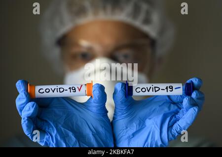 Femme en costume de protection, respirateur et lunettes tenant des tubes à essai avec échantillon d'analyse infectés et non infectés par le coronavirus COVID-19 à Kiev, Ukraine, on 23 mars 2020. (Photo Illustration par Maxym Marusenko/NurPhoto) Banque D'Images